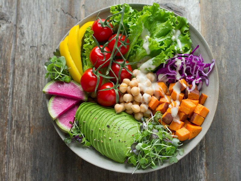Vegetable bowl with avocado, tomatoes, chickpeas and leafy greens