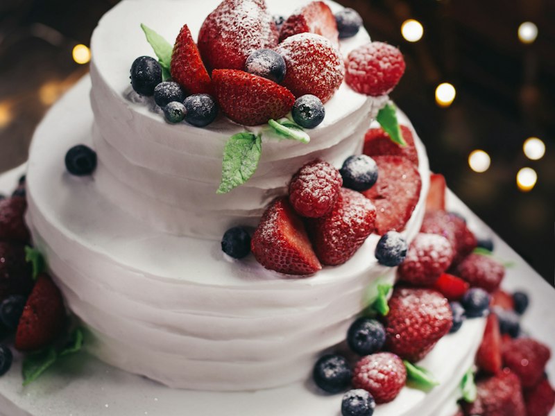 White layered cake topped with strawberries and blueberries